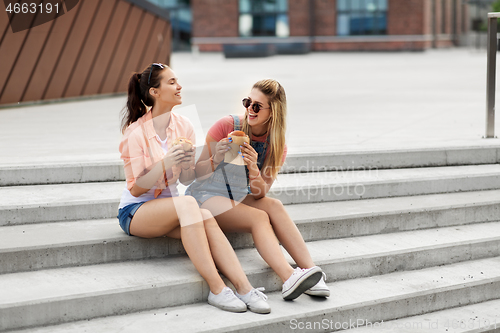 Image of teenage girls or friends eating burgers outdoors