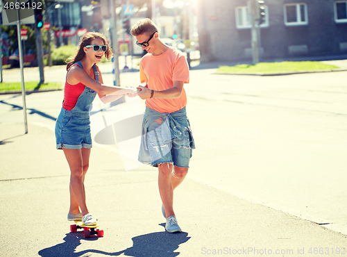 Image of teenage couple riding skateboards on city street