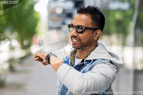 Image of indian man recording voice message by smart watch