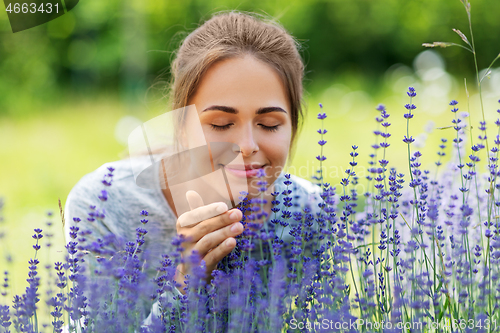 Image of young woman smelling lavender flowers in garden