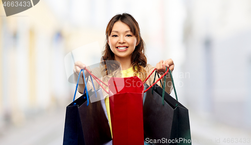 Image of happy asian woman with open shopping bags