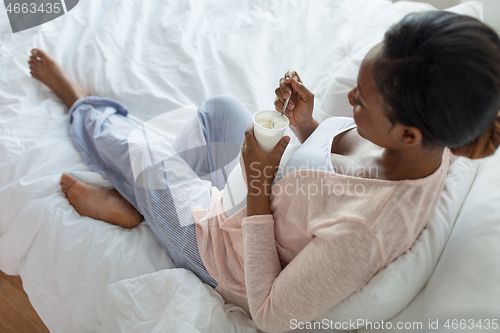 Image of pregnant woman eating yogurt for breakfast in bed