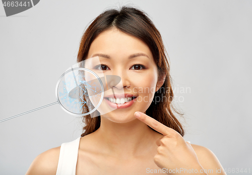 Image of happy smiling young asian woman touching her face