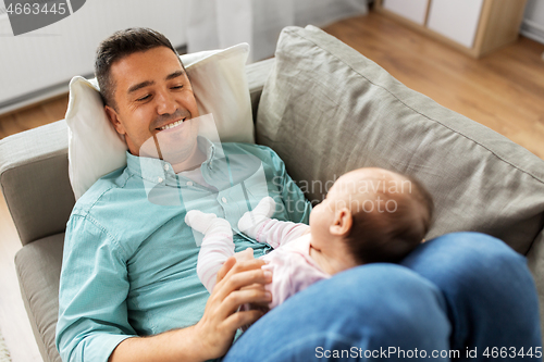 Image of middle aged father with baby lying on sofa at home