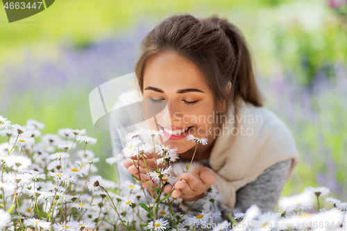 Image of close up of woman smelling chamomile flowers