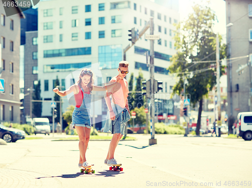 Image of teenage couple riding skateboards on city street