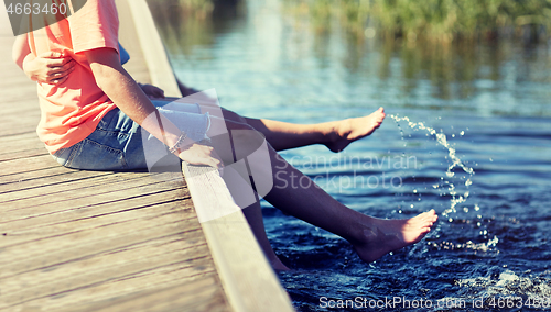 Image of happy teenage couple sitting on river berth