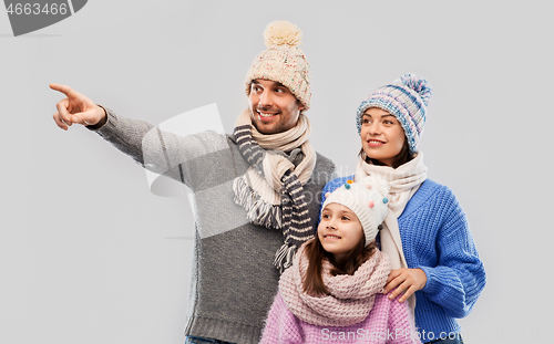 Image of happy family in winter clothes on grey background