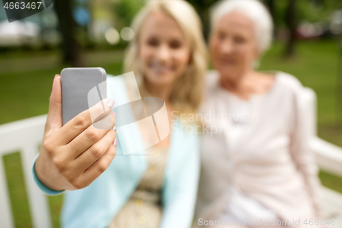 Image of daughter and senior mother taking selfie at park