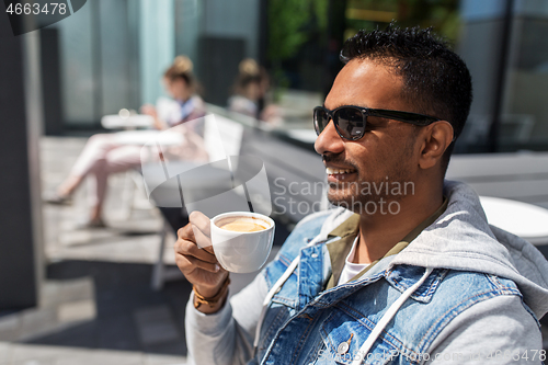 Image of indian man drinking coffee at city street cafe