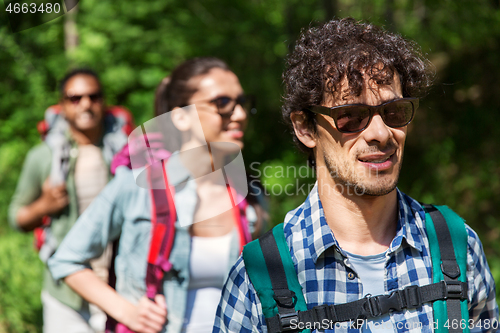 Image of group of friends with backpacks hiking in forest