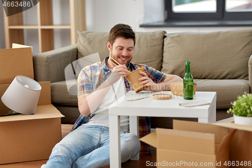 Image of smiling man eating takeaway food at new home