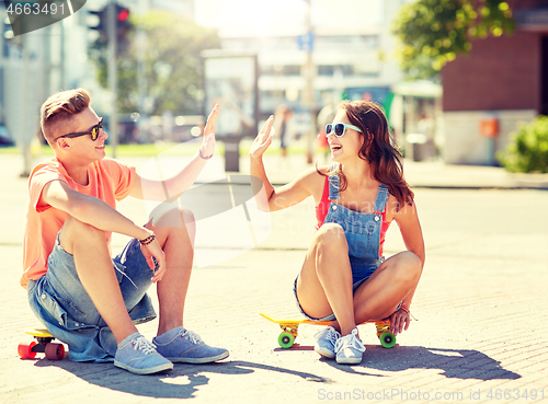 Image of teenage couple with skateboards on city street