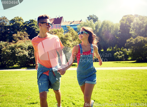 Image of happy teenage couple walking at summer park