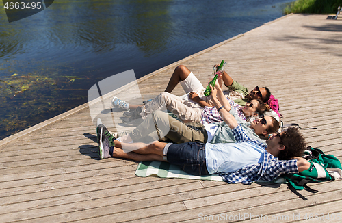 Image of friends drinking beer and cider on lake pier