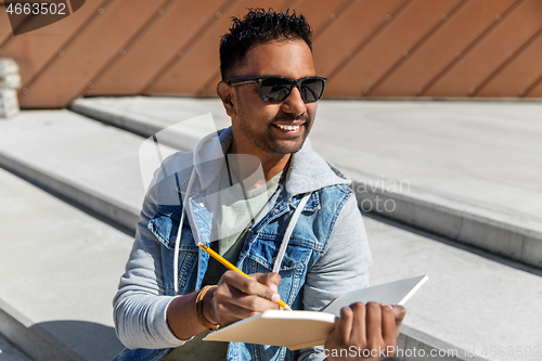 Image of indian man with notebook or sketchbook on roof top