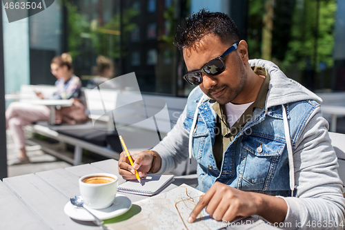 Image of man with map and notebook at street cafe in city