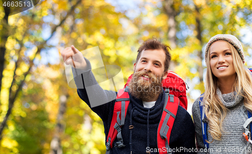 Image of smiling couple with backpacks hiking in autumn