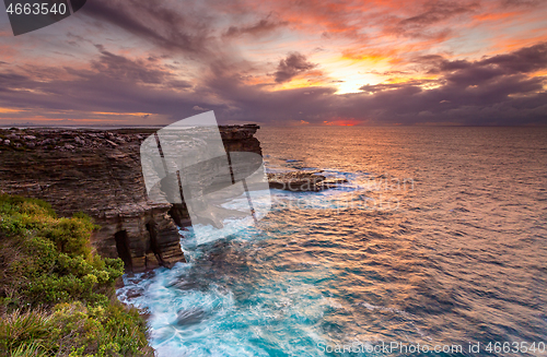 Image of Sunrise over the ocean and the crumbling headland cliffs 