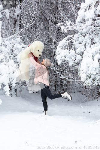 Image of Happy go lucky woman frolicking in snow holding large soft toy