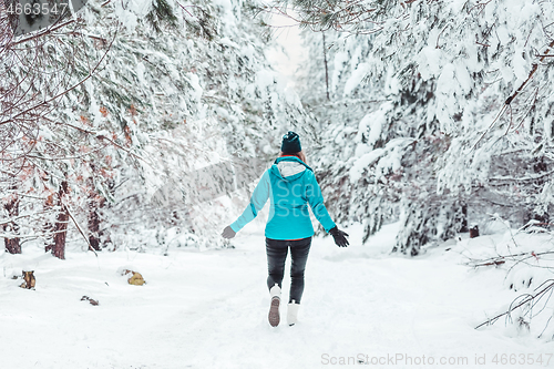 Image of Woman walking in a snow covered forest