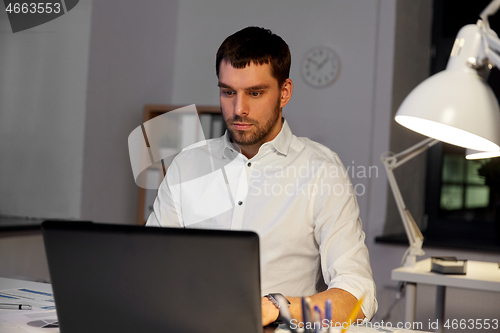 Image of businessman with laptop working at night office