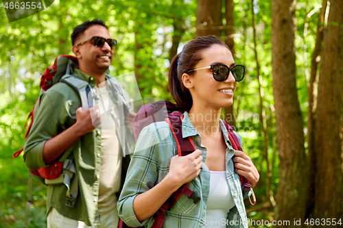 Image of mixed race couple with backpacks hiking in forest