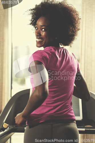 Image of afro american woman running on a treadmill