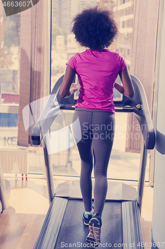 Image of afro american woman running on a treadmill