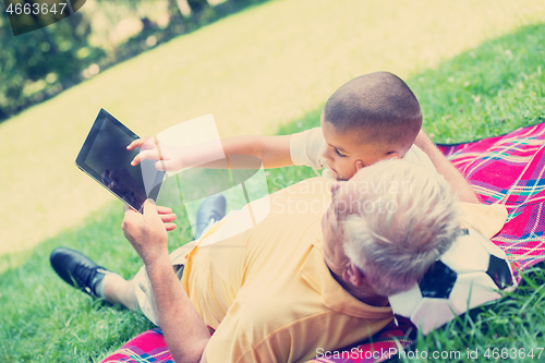 Image of grandfather and child in park using tablet