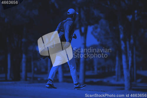 Image of golf player walking and carrying bag