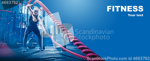 Image of Woman with battle rope battle ropes exercise in the fitness gym.