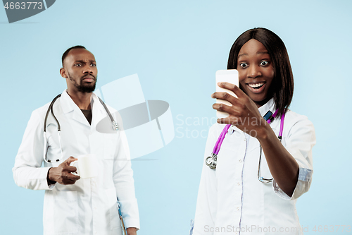 Image of The female and male happy afro american doctors on blue background