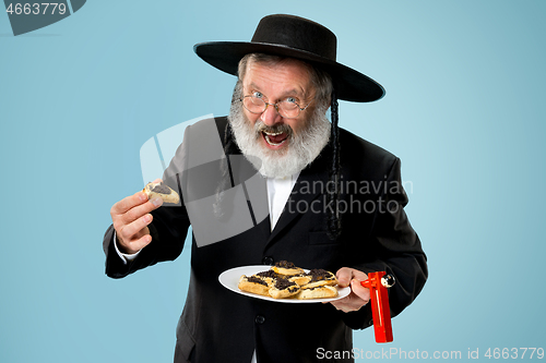 Image of The senior orthodox Jewish man with black hat with Hamantaschen cookies for Jewish festival of Purim