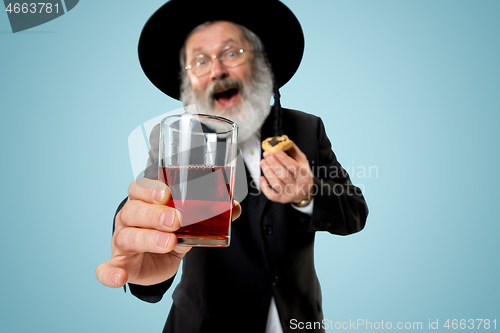 Image of The senior orthodox Jewish man with black hat with Hamantaschen cookies for Jewish festival of Purim