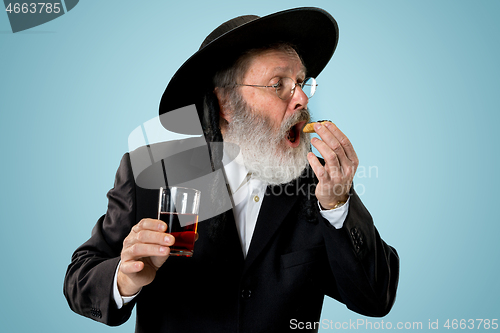 Image of The senior orthodox Jewish man with black hat with Hamantaschen cookies for Jewish festival of Purim