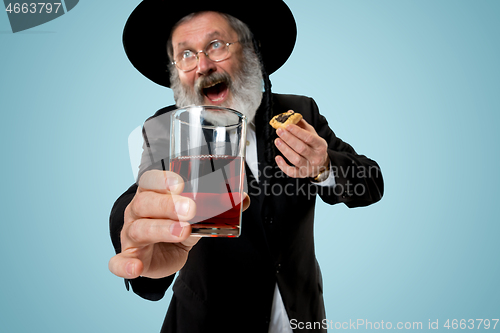 Image of The senior orthodox Jewish man with black hat with Hamantaschen cookies for Jewish festival of Purim