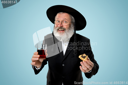 Image of The senior orthodox Jewish man with black hat with Hamantaschen cookies for Jewish festival of Purim