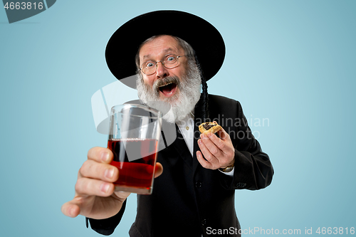 Image of The senior orthodox Jewish man with black hat with Hamantaschen cookies for Jewish festival of Purim