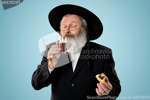 Image of The senior orthodox Jewish man with black hat with Hamantaschen cookies for Jewish festival of Purim