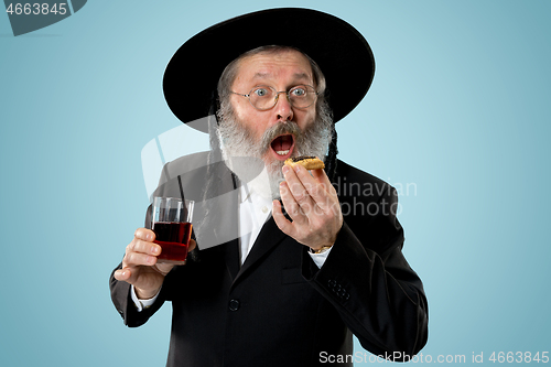 Image of The senior orthodox Jewish man with black hat with Hamantaschen cookies for Jewish festival of Purim