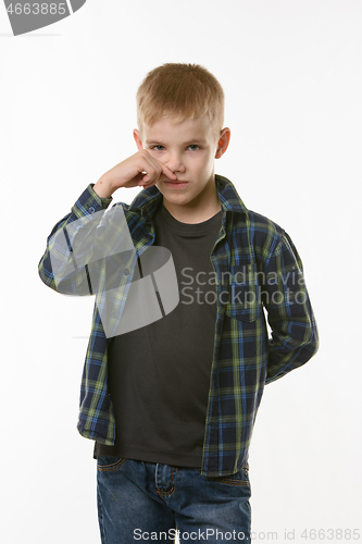 Image of A ten year old boy wipes his nose with his finger