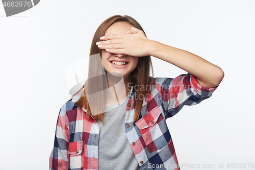 Image of Emotional joyful teen girl covering her eyes with palm