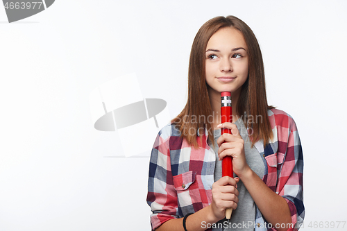 Image of Smiling girl holding big pencil and looking to the side