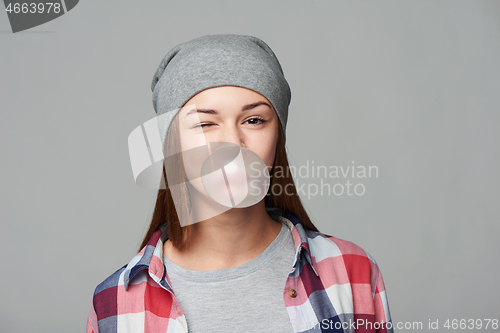 Image of Smiling teen girl blowing bubblegum winking at you