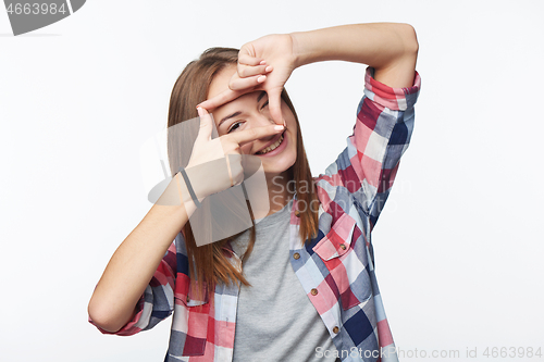 Image of Smiling teen girl looking at camera through finger frame