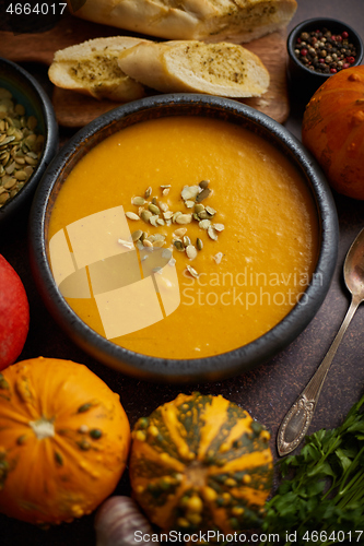 Image of Homemade vegetarian pumpkin cream soup served in ceramic bowl. Decorated with seeds