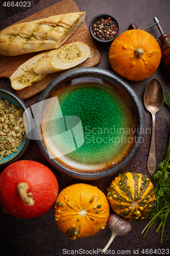 Image of Empty ceramic bowl and ingredients ready for pumpkin soup. With different kinds of small pumpkins