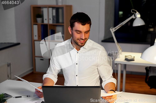 Image of businessman with papers working at night office