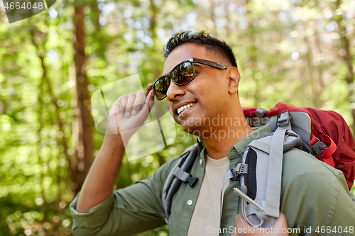 Image of happy indian man with backpack hiking in forest